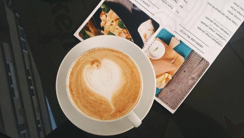 Coffee cup beside a menu on a restaurant table